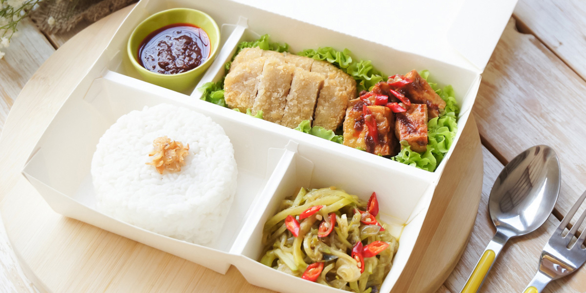 A lunch box with rice, vegetables and meat in it, perfect for a quick meal at work or on the go.