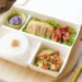 A lunch box with rice, vegetables and meat in it, perfect for a quick meal at work or on the go.