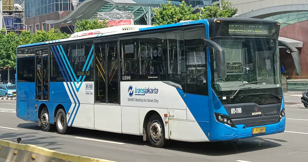 A blue and white business bus driving down a city street.