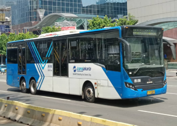 A blue and white business bus driving down a city street.